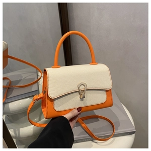 Detail view of contrast color handbag with woven flap and gold water-drop metal clasp