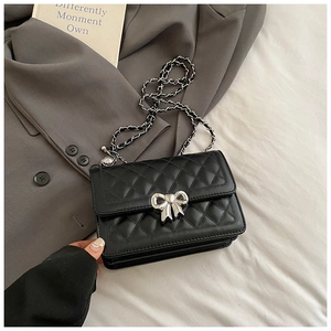 Detail of black quilted leather crossbody bag featuring a silver bow-shaped twist lock