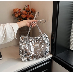 Close-up of silver sequin tote bag with woven handle and metallic logo plaque