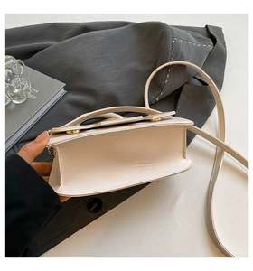Detail view of the beige crossbody bag interior and golden metallic buckle hardware