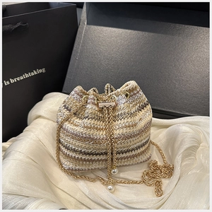 Détails d'un sac seau tissé avec bandoulière en chaîne dorée et perles élégantes