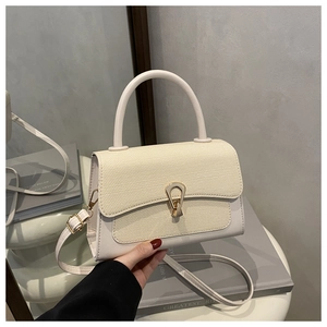 Detail of cream leather handbag with woven texture flap and golden horseshoe lock