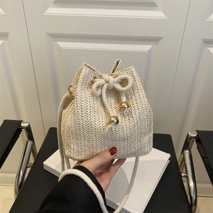 Chic woven straw bucket bag in cream white with rope shoulder strap for beach vacation