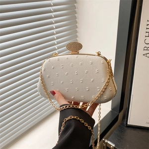 Elegant ivory fabric clutch bag with dotted texture and diamond-set gold metal clasp