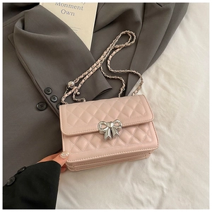 Detail of light pink quilted leather bag featuring a silver bow-shaped lock and metal chain
