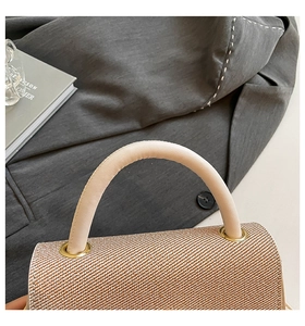 Macro detail of weaving texture, cream leather handle, and golden metal rings on the bag