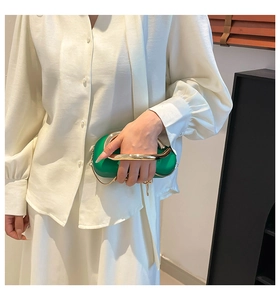 Detail of a bright green leather evening bag with chunky gold metal handle and chain