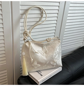 Detail of white lace jacquard shoulder bag with 3D butterfly appliqués and tassel zipper