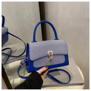 Detail of navy leather and blue striped fabric contrast handbag with gold horseshoe buckle