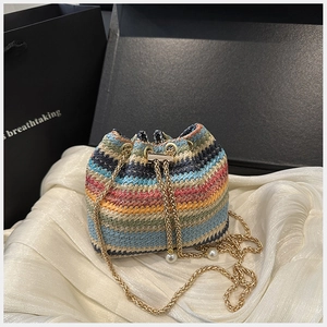 Détail du sac seau tissé à rayures colorées avec cordon perlé et chaîne dorée