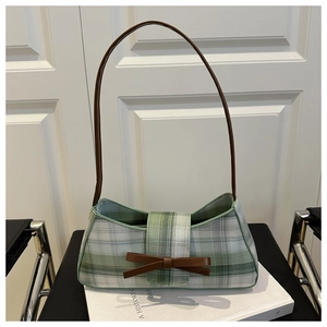 Detail of green and white plaid underarm bag with a brown leather bow decoration