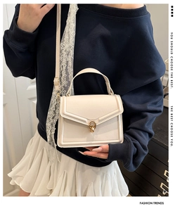 Vue détaillée du sac à main en cuir crème avec fermoir doré et bandoulière en dentelle blanche