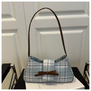 Close-up of blue and white checkered underarm bag with a brown leather bow detail