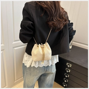 Detail of woven bucket bag featuring gold chain strap and pearl drawstring accents
