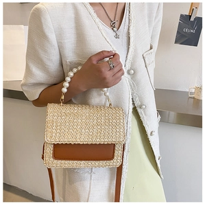 Detail of straw woven handbag with large pearl handle and adjustable brown leather strap