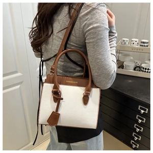 Detail of a brown and white contrast leather handbag with FASHION & BAGS lettering