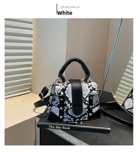 Close-up of snake skin pattern handbag with gold studs and black handle detail