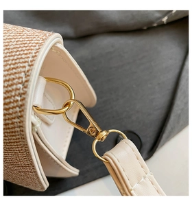 Detail of woven fabric handbag with cream leather trim and gold metal lobster clasp