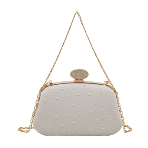 Elegant cream evening clutch with quilted texture, gold chain strap, and rhinestone clasp