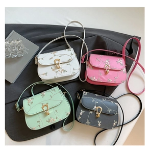 Close-up of four floral embroidered crossbody bags with pearl chains and gold clasps