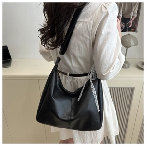 Detail of black faux leather tote with white lace bow on shoulder of a model