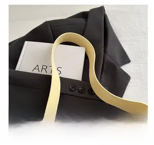 Detail of soft pale yellow faux leather strap on minimalist chic underarm bag