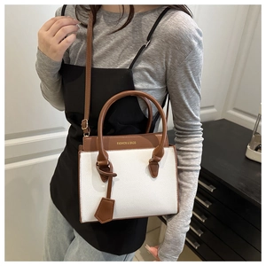 Brown and white bicolor tote bag shown crossbody on model for size perspective