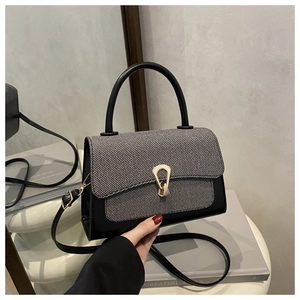 Detail of contrast color crossbody bag with tweed texture flap and golden horseshoe buckle