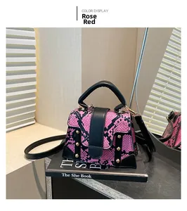 Detail of rose red and black snakeskin pattern crossbody bag with gold rivet accents