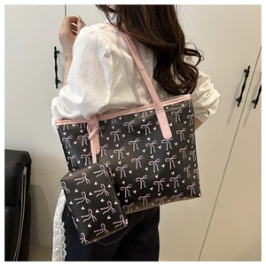 Détail du sac fourre-tout noir à nœuds roses avec un petit porte-monnaie assorti attaché