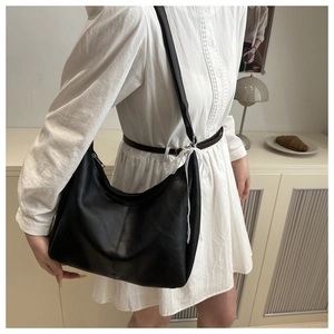 Detail of black semi-moon underarm bag with vertical stitching and lace tie accent