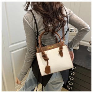 Detail showing white faux leather tote with brown handles and shoulder strap on model