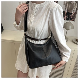 Close-up of black leather tote bag featuring elegant white lace trim and wide strap