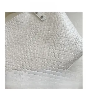 Close-up of white woven texture and metallic rivet detail on a stylish shoulder tote bag