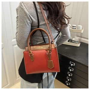 Detail of red and brown contrast stitching tote bag with gold hardware and logo