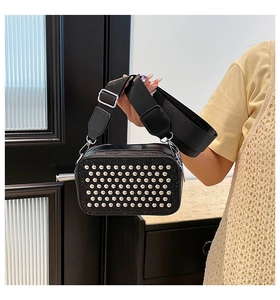 Détail du sac bandoulière noir avec rivets argentés et large sangle en nylon