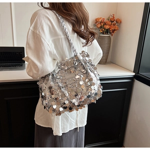 Silver sequin tote bag shown on shoulder with woven strap and metallic finish