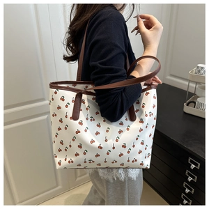 Gros plan détaillé du sac cabas vintage à motif cerise avec finitions en cuir brun