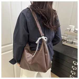 Detail of brown faux leather tote with decorative white lace ribbon on shoulder strap