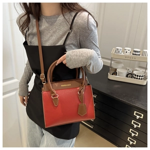 Detail of red and brown patchwork leather handbag with litchi texture and gold hardware