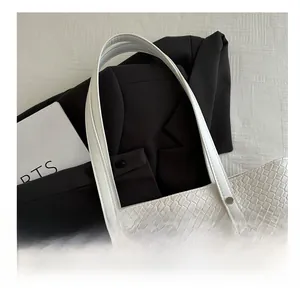 Detail of white tote bag with woven texture, leather handle and silver metal rivets