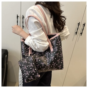 Détail du sac cabas à imprimé nœud avec pochette assortie porté par un mannequin en studio