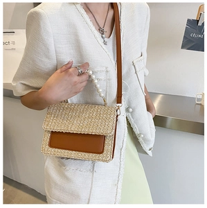 Detail of hand-woven straw bag with elegant pearl handle and brown leather shoulder strap