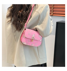 Detailed view of pink shoulder bag with white floral embroidery and golden twist lock