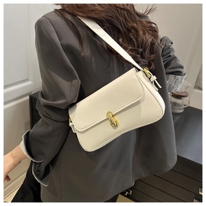 Detailed close-up of a cream white shoulder bag with a gold metal lock on a grey suit