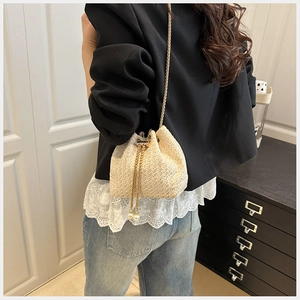 Detail view of woven bucket bag with golden chain drawstring and pearl accents