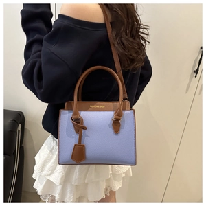 Detail of light blue lychee pattern tote with brown handles and gold fashion text