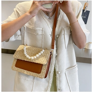 Detail of woven straw shoulder bag with pearl handle and brown leather pocket detail