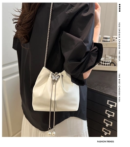 Detail of white crocodile pattern bucket bag with butterfly buckle and pearl tassels