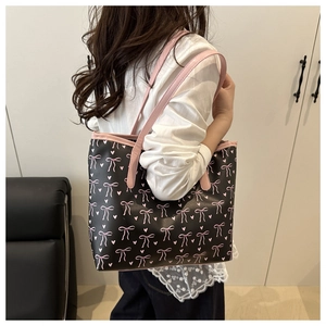 Sac fourre-tout noir avec nœuds roses et cœurs porté à l'épaule par un mannequin
